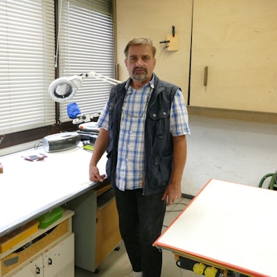 Restaurator Roland Gassert steht an seinem Arbeitsplatz, einem Schreibtisch, in seiner Werkstatt.