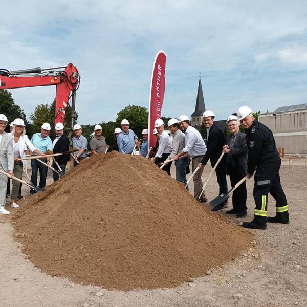 Viele Personen beim Spatenstich eines Gebäudes.