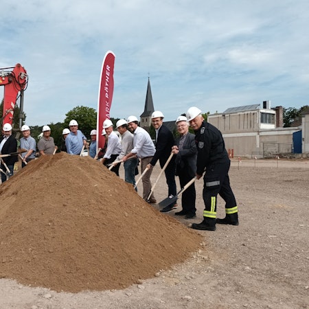 Viele Personen beim Spatenstich eines Gebäudes.