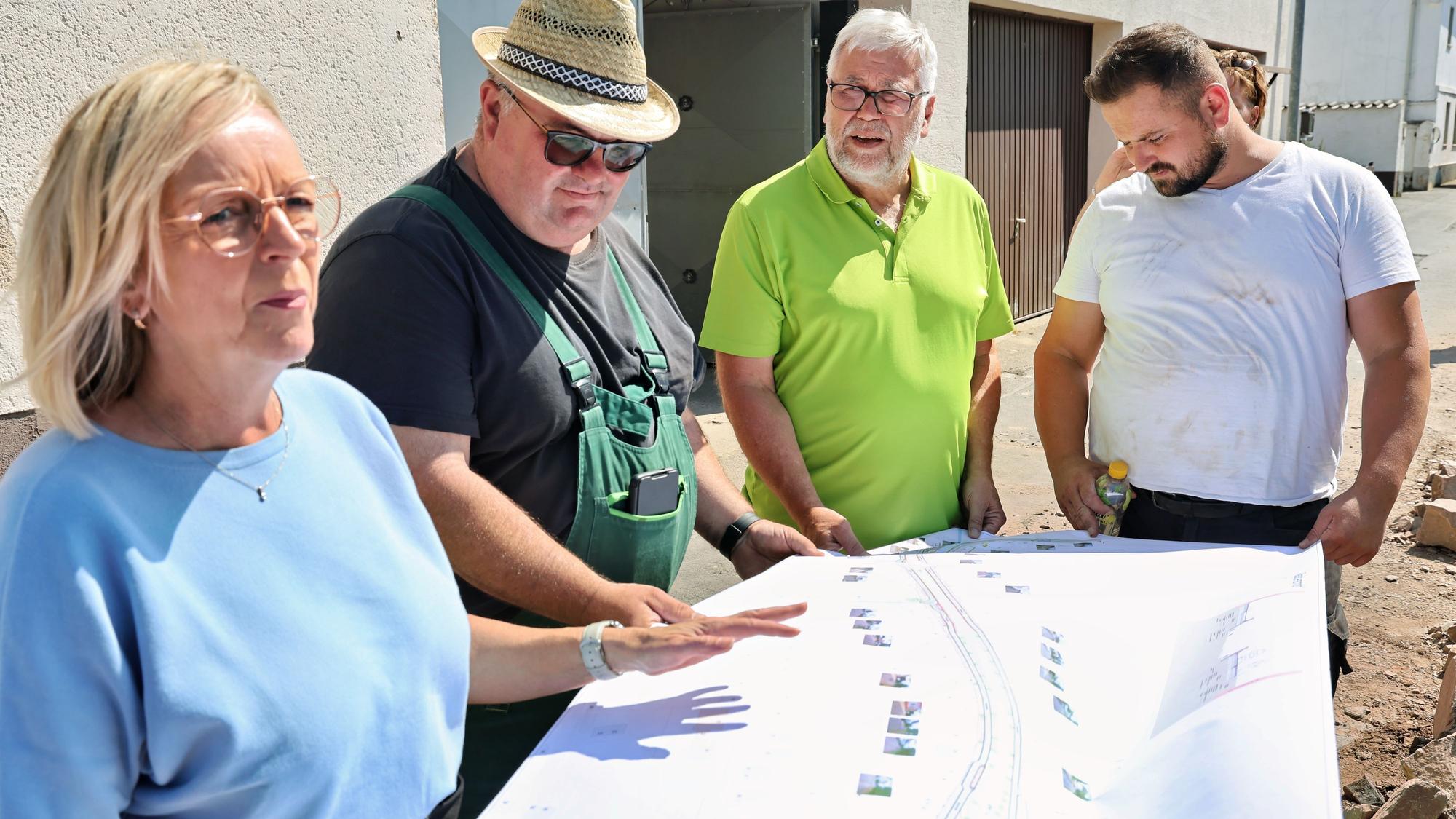 Sabine Preiser-Marian, Reiner Jansen, Christian Lorenz und einer der Arbeiter halten einen Bauplan fest.