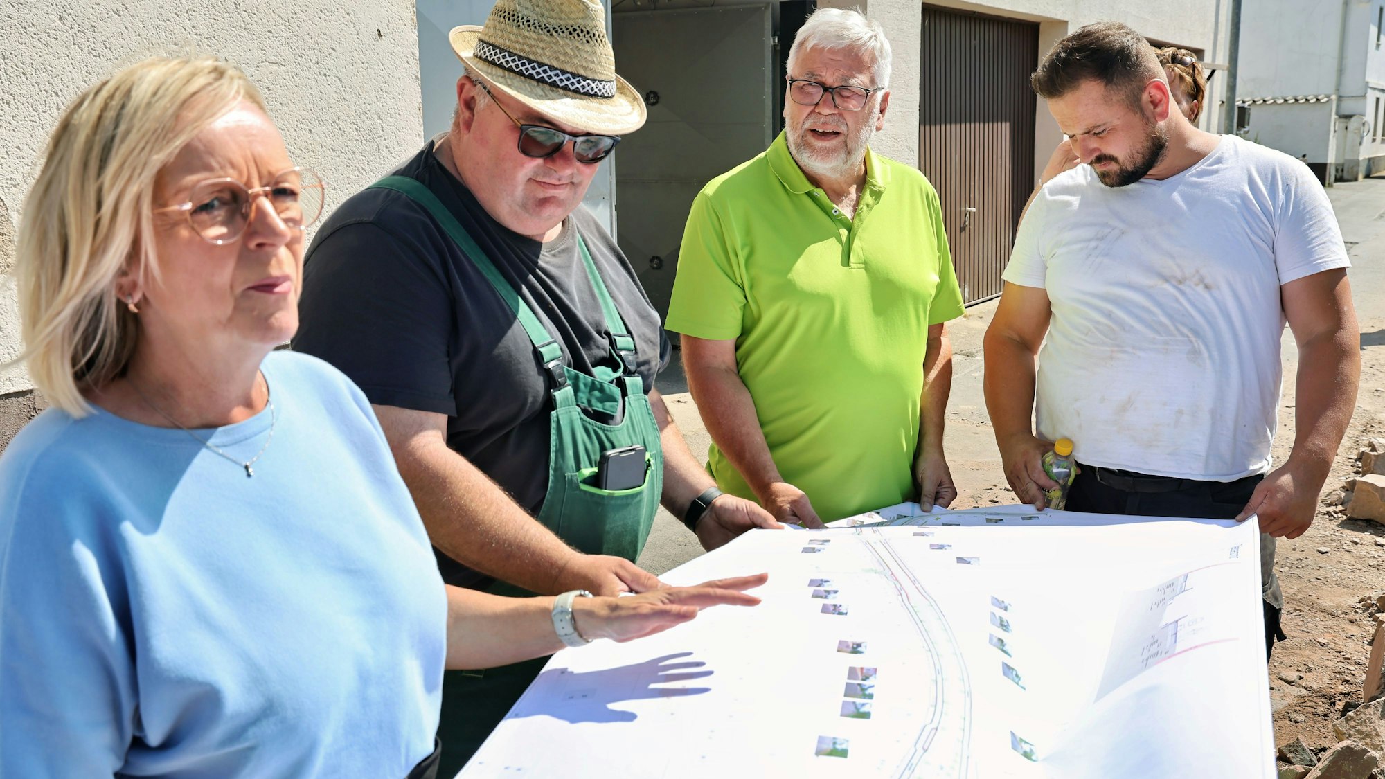Sabine Preiser-Marian, Reiner Jansen, Christian Lorenz und einer der Arbeiter halten einen Bauplan fest.