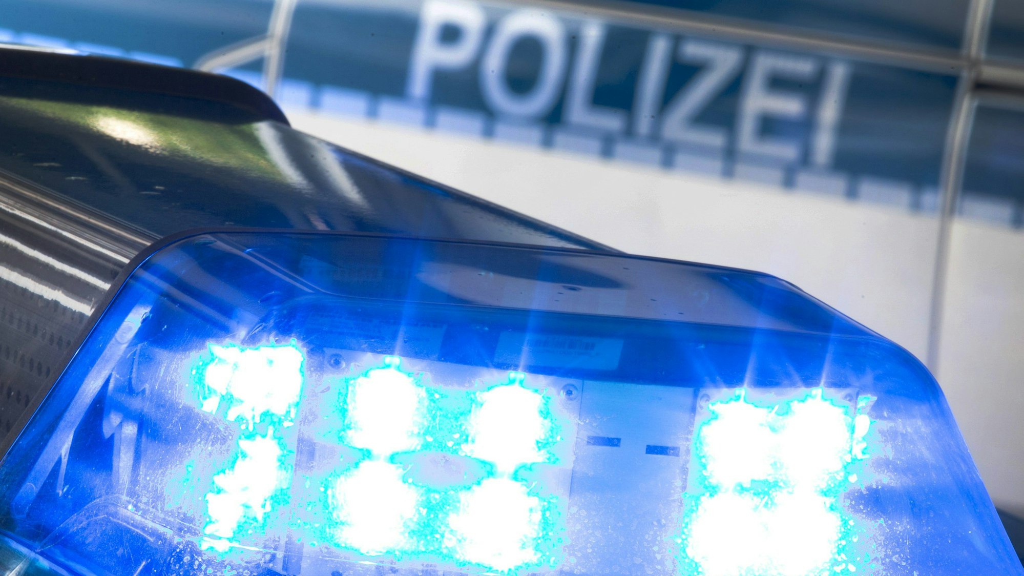 Eine Blaulicht leuchtet auf dem Dach eines Polizeiwagens.