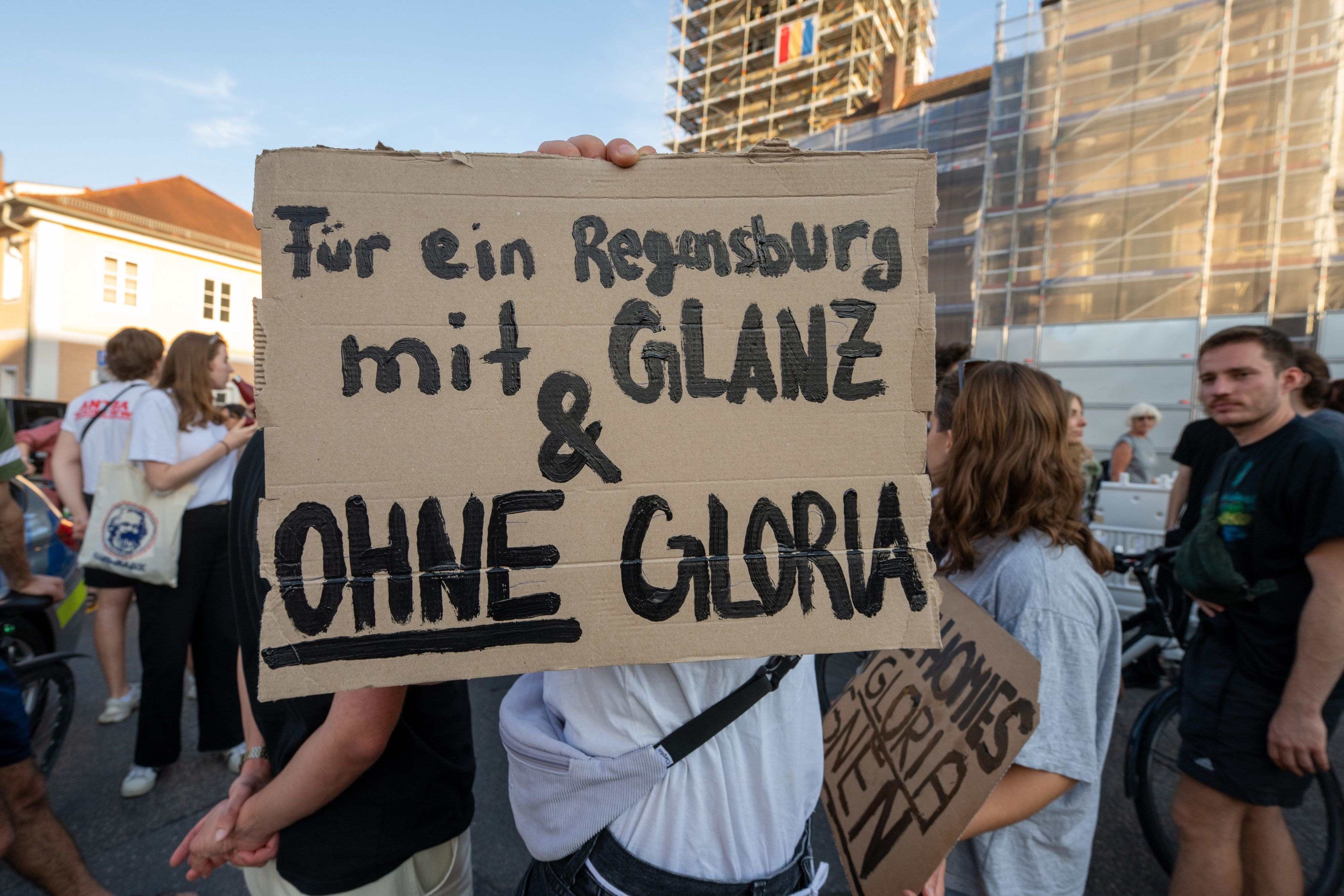 14.07.2023, Bayern, Regensburg: Ein Schild mit der Aufschrift "Für ein Regensburg mit Glanz & ohne Gloria" wird während einer Demonstration vor dem Fürstenschloss St. Emmeram in die Höhe gehalten. Zu Beginn der Regensburger Schlossfestspiele haben etwa 300 Menschen vor Schloss Thurn und Taxis demonstriert. Ihr Protest richtete sich unter anderem gegen umstrittene Aussagen der Hausherrin, Gloria Fürstin von Thurn und Taxis, unter anderem zum Thema Homosexualität. Foto: Armin Weigel/dpa +++ dpa-Bildfunk +++
