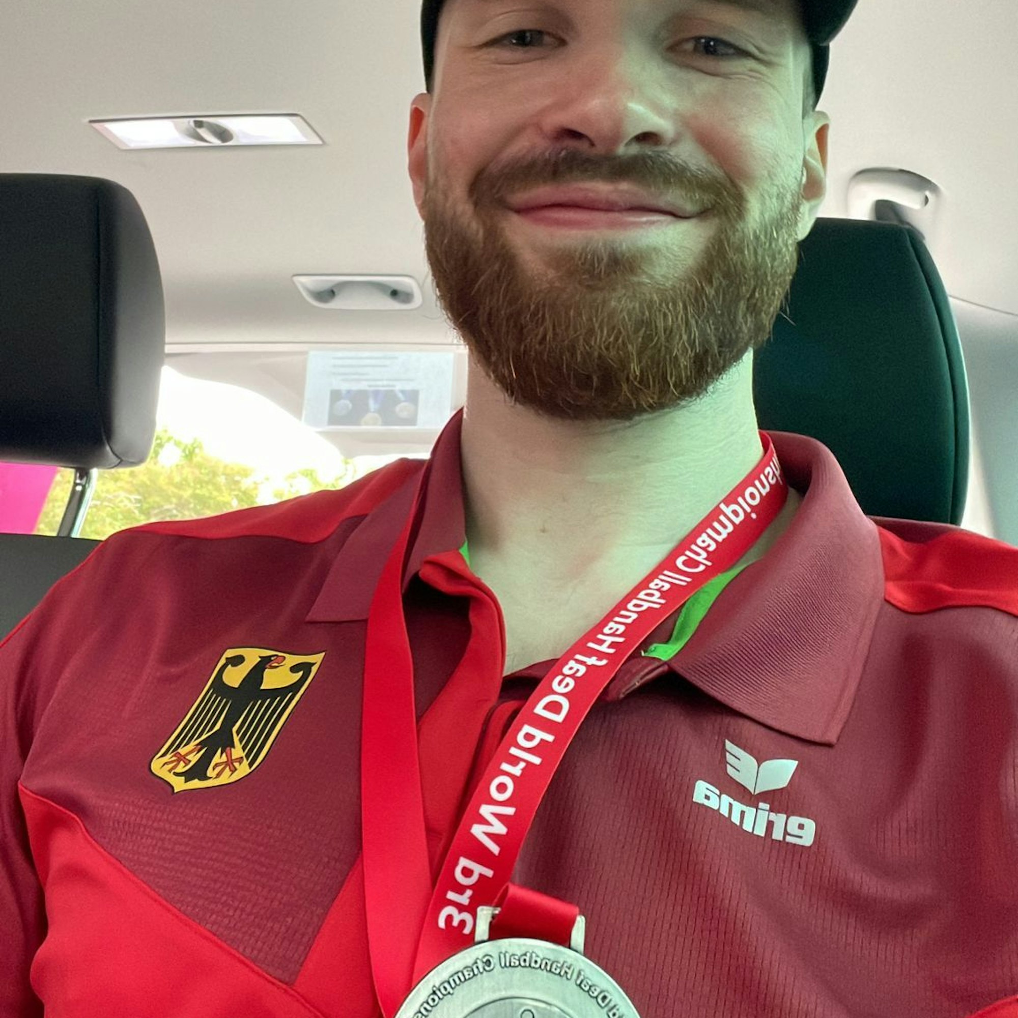 Simon Schöller lächelt und hält die Silbermedaille in die Kamera.