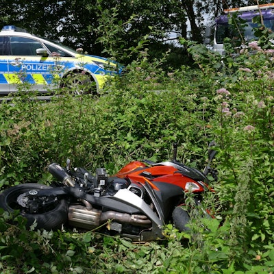 Ein Motorrad liegt in einem Straßengraben. Auf der Straße steht ein Polizeiauto.