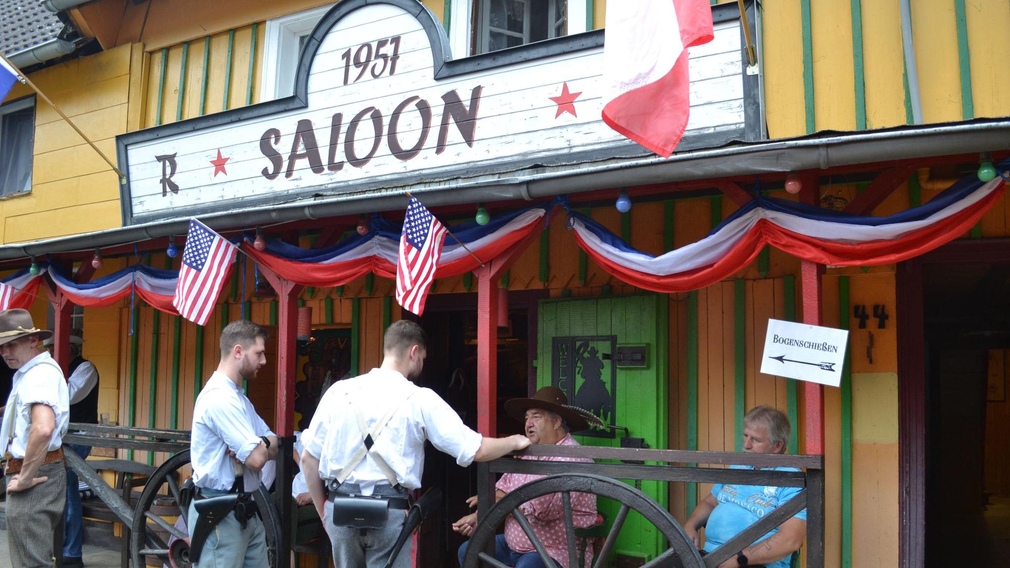 Männer stehen vor einem Wildwest-Saloon.