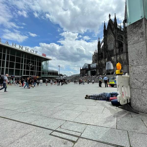 Im Schatten des Kölner Doms liegt ein Obdachloser auf dem Bahnhofsvorplatz.