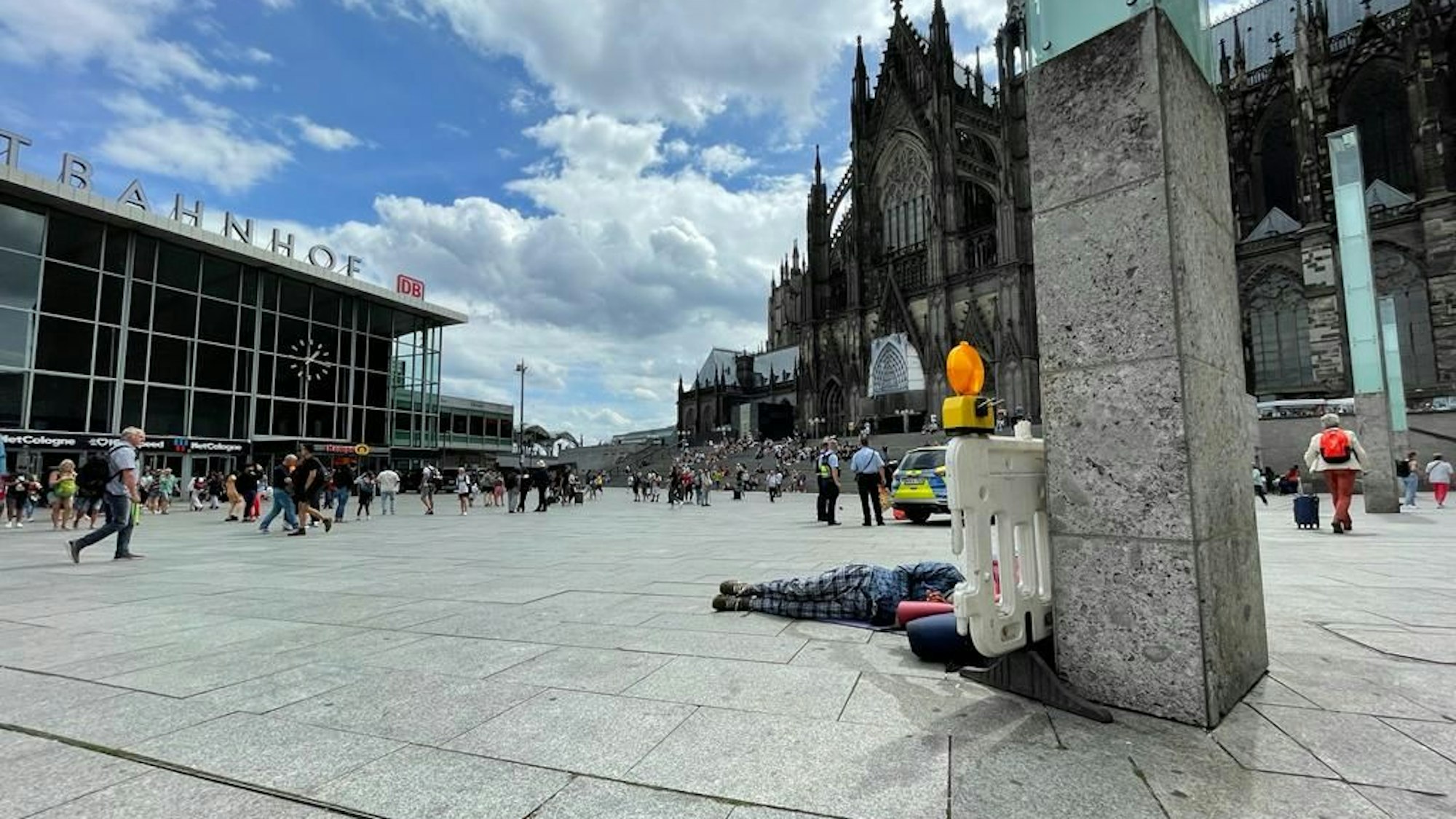 Im Schatten des Kölner Doms liegt ein Obdachloser auf dem Bahnhofsvorplatz.