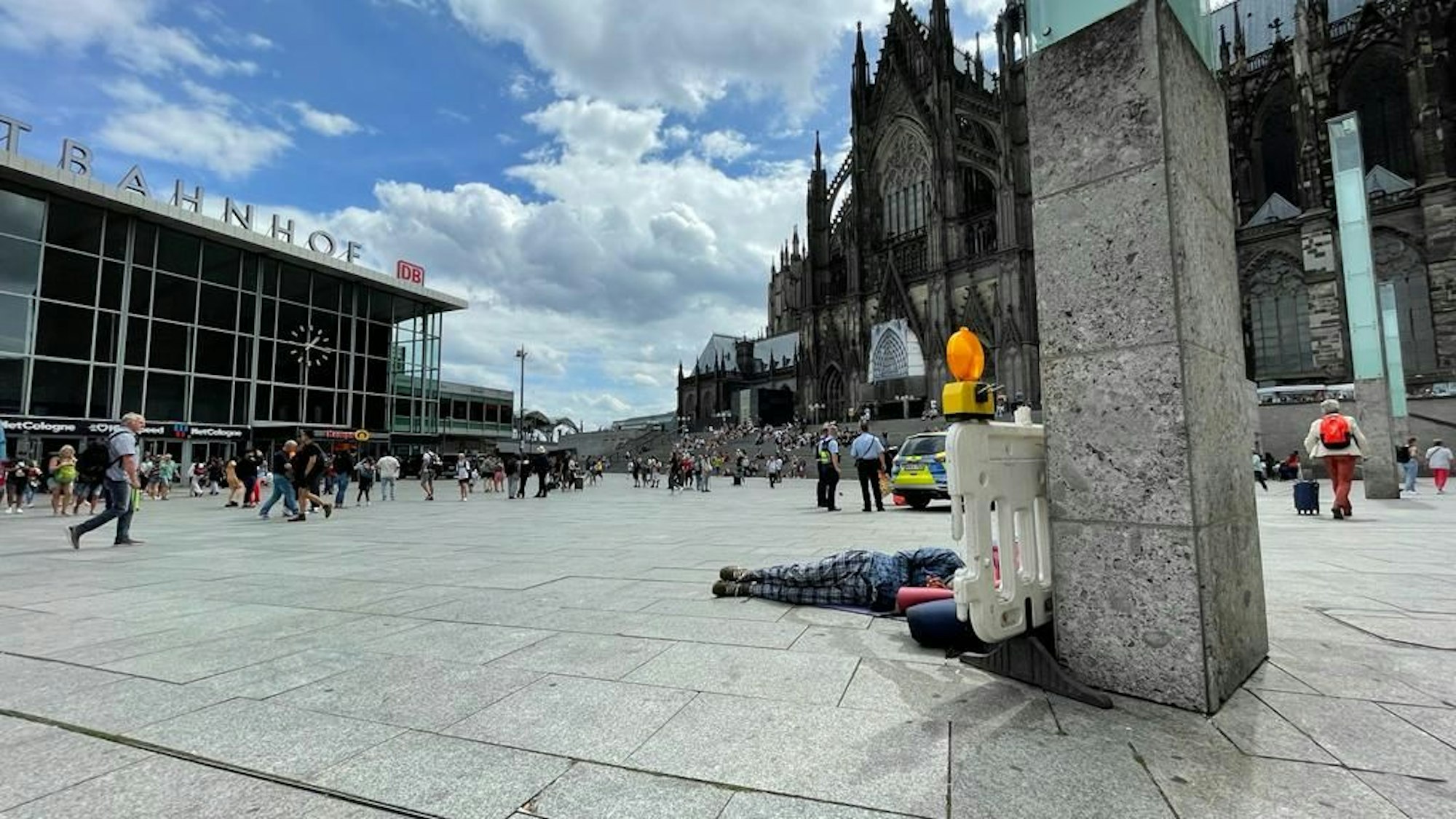 Im Schatten des Kölner Doms liegt ein Obdachloser auf dem Bahnhofsvorplatz.