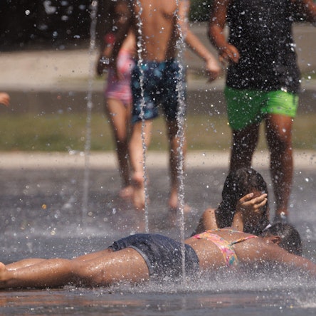 Kinder kühlen sich in einem Brunnen ab.