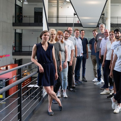 Mehrere Männer und Frauen stehen für ein Gruppenfoto in einem Treppenhaus zusammen.
