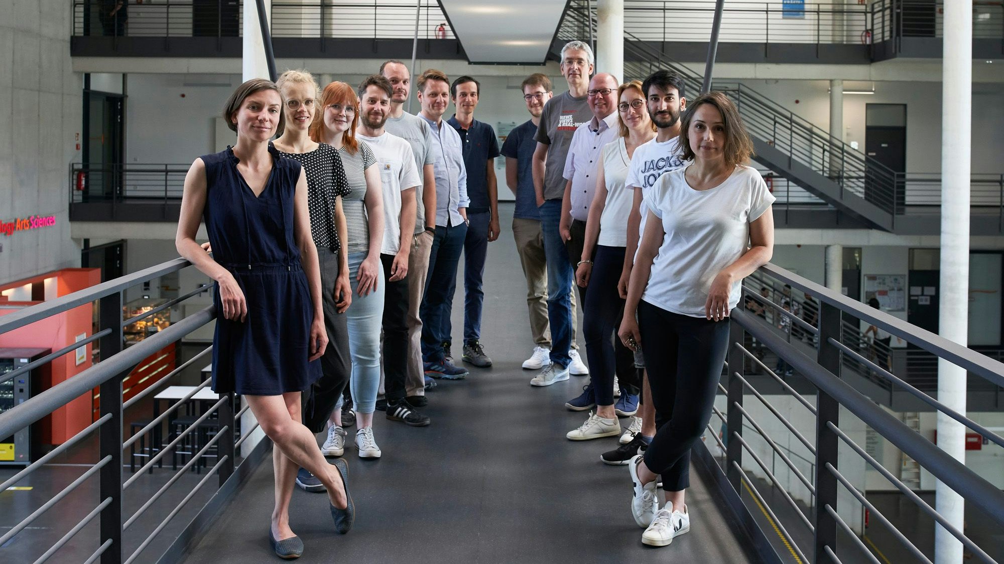 Mehrere Männer und Frauen stehen für ein Gruppenfoto in einem Treppenhaus zusammen.