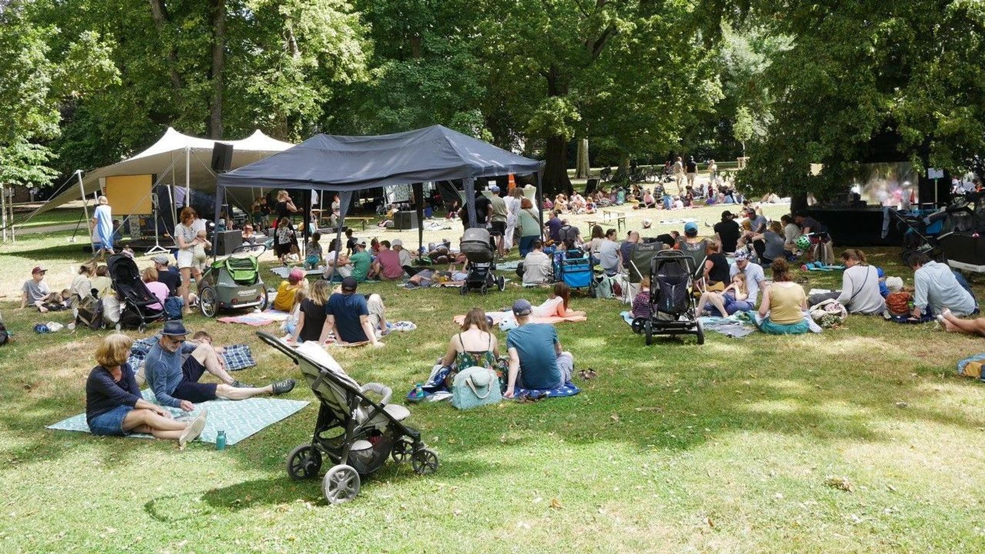 Menschen sitzen auf einer Wiese im Stadtgarten.