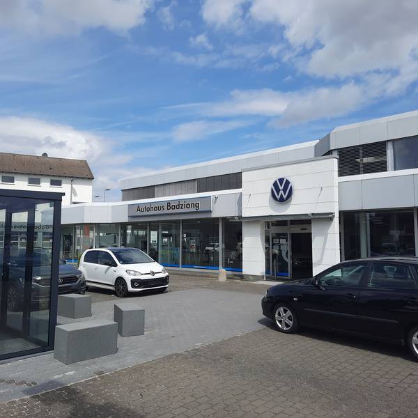 Der Eingang des Autohaus Badziong, drei Autos stehen davor auf dem Platz.