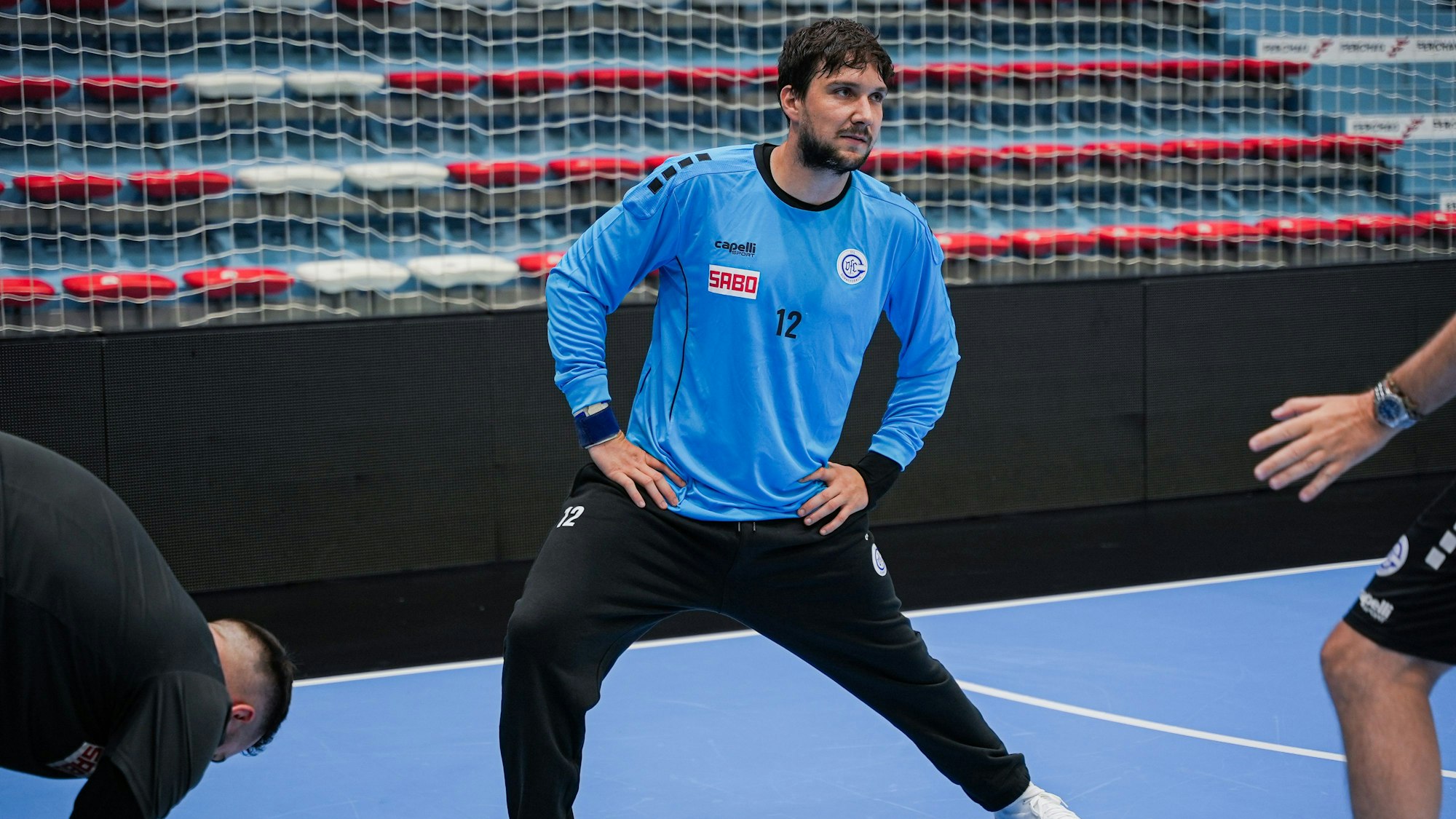 Ein Handball-Torhüter dehnt sich beim Training in einer Sporthalle.