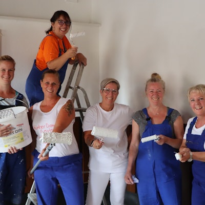 Mehrere Frauen der 1. Hürther Damengarde „Hürther Hätzje“ sind mit Pinseln, Rollen und Farbe auf dem Foto zu sehen.