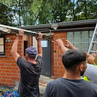 Männer heben ein altes Dach von einer Baracke. Das Tierheim in Niederaußem erhält Neubauten. Die alten Baracken werden abgerissen.