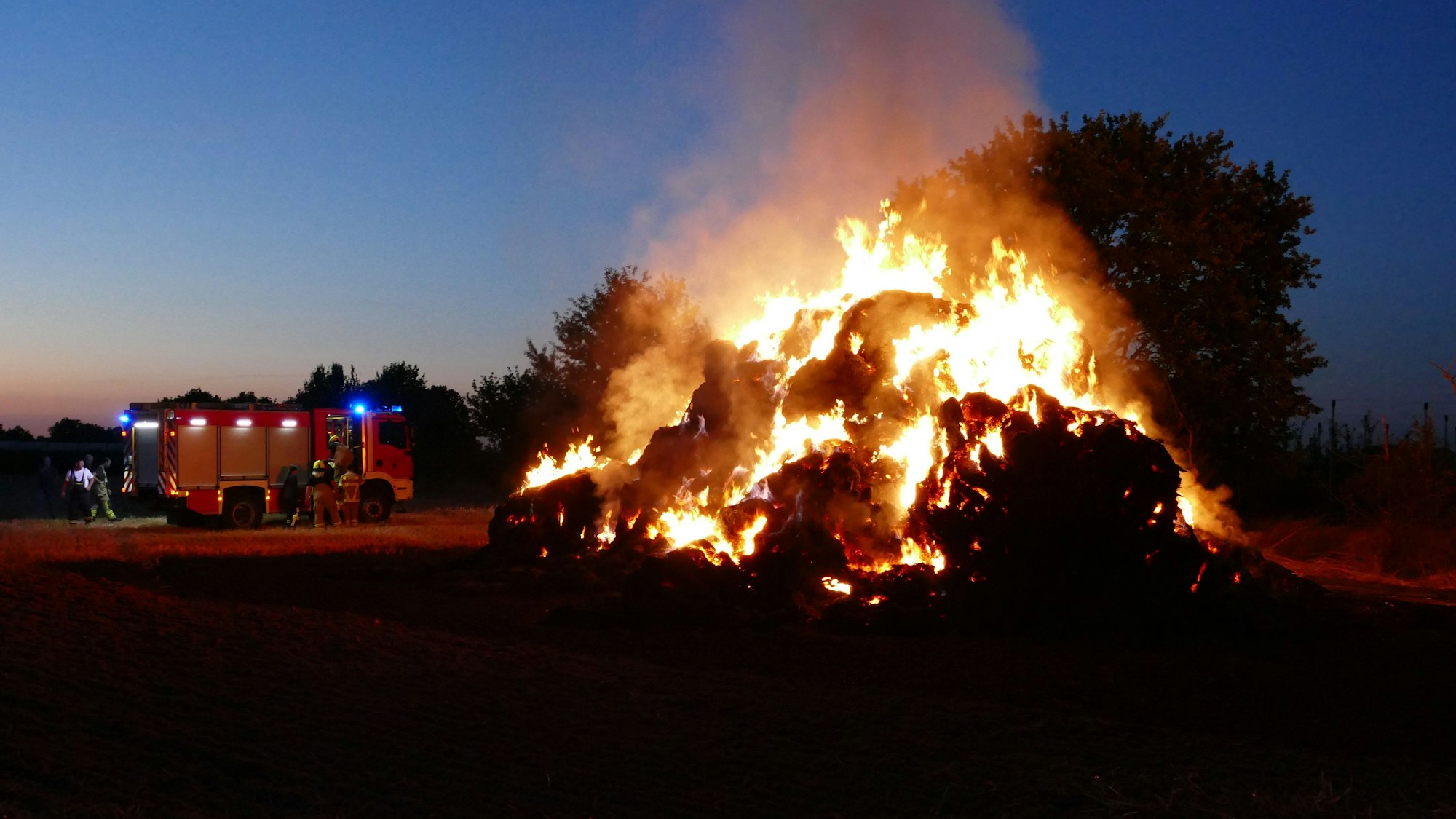 Loderndes Feuer in Rheinbach: Ein Strohfeuer sorgte für Aufsehen. Im Hintergrund ist ein Feuerwehrwagen zu sehen.