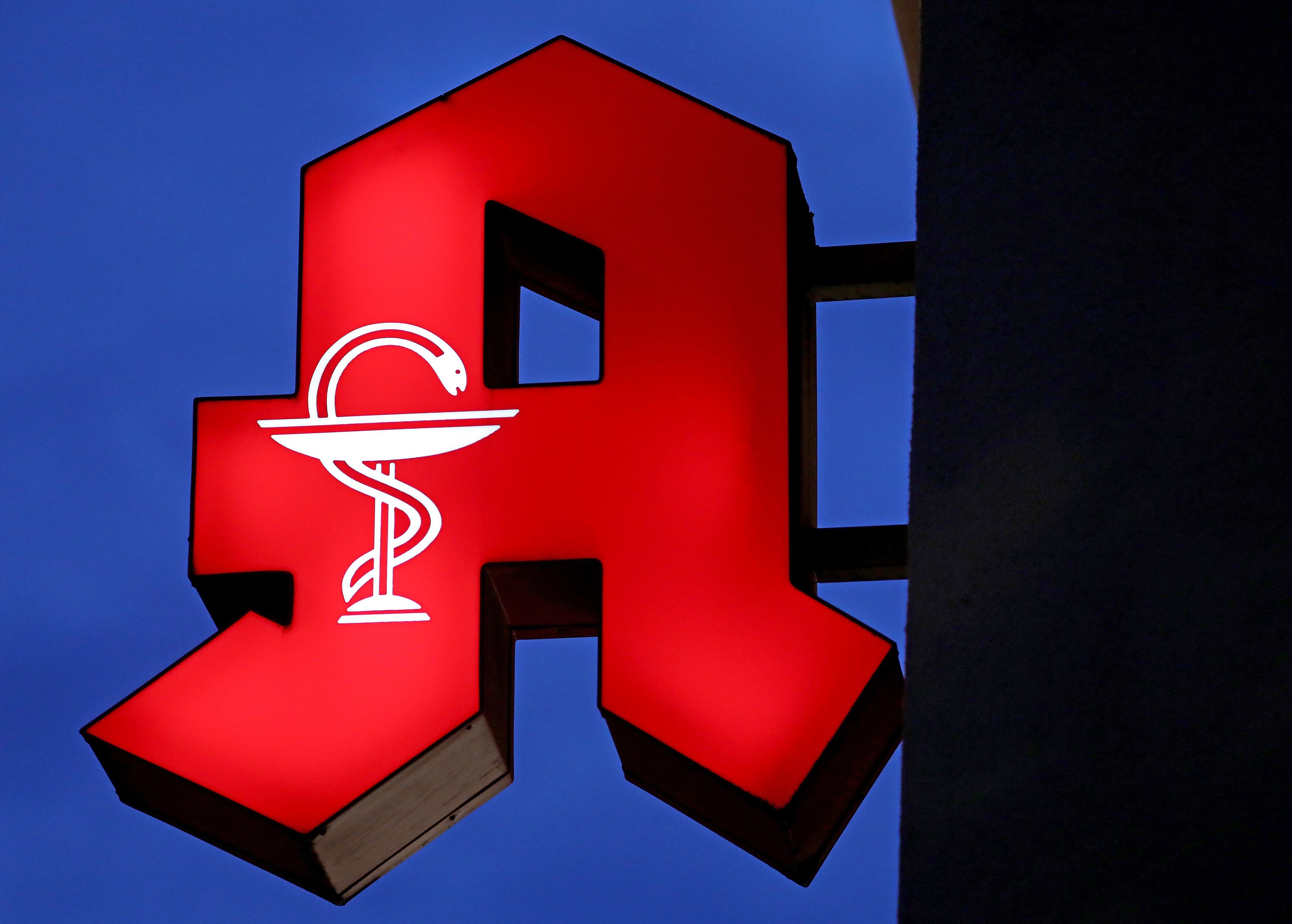 Das Apotheken-Logo leuchtet an einer Apotheke.