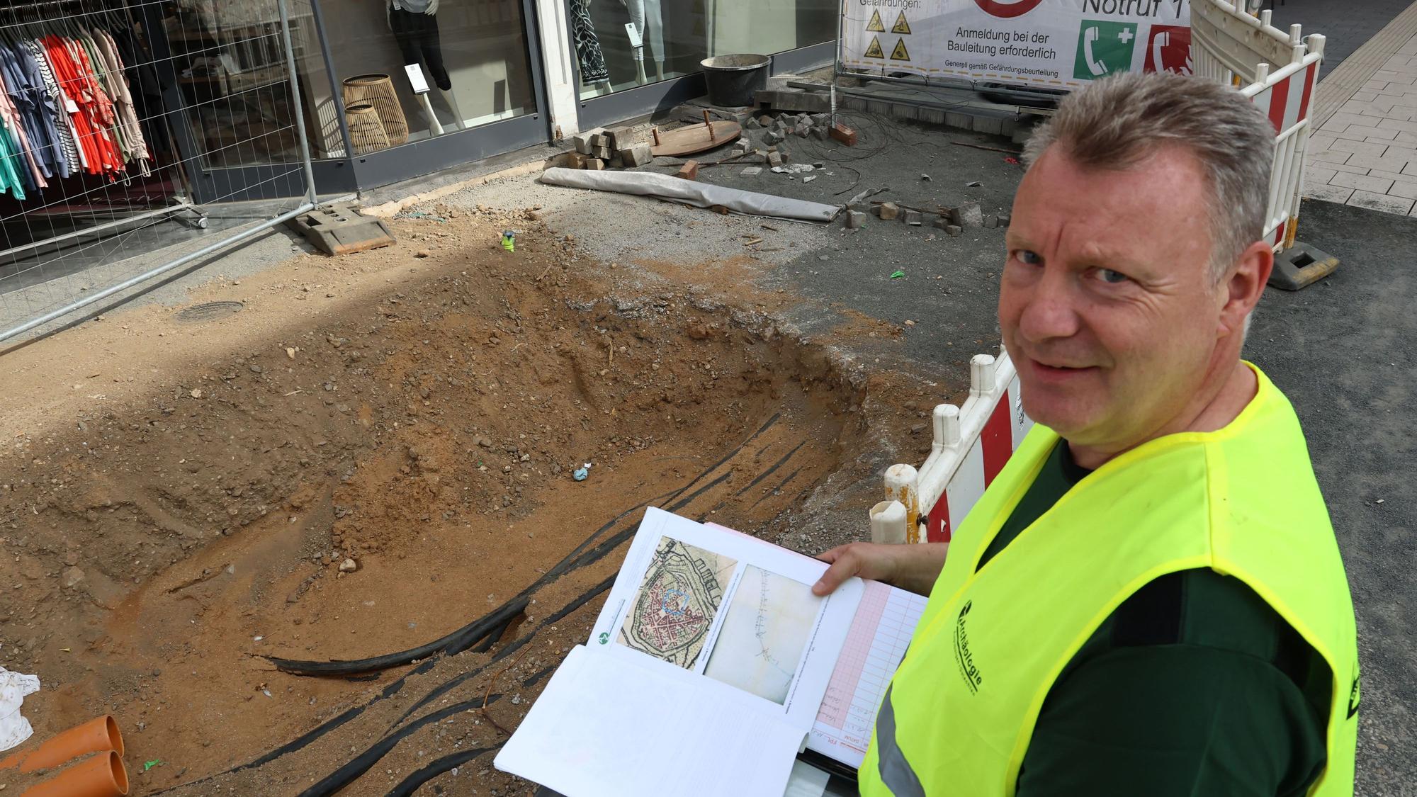 Der Grabungsleiter mit Unterlagen am Rande der Baugrube.
