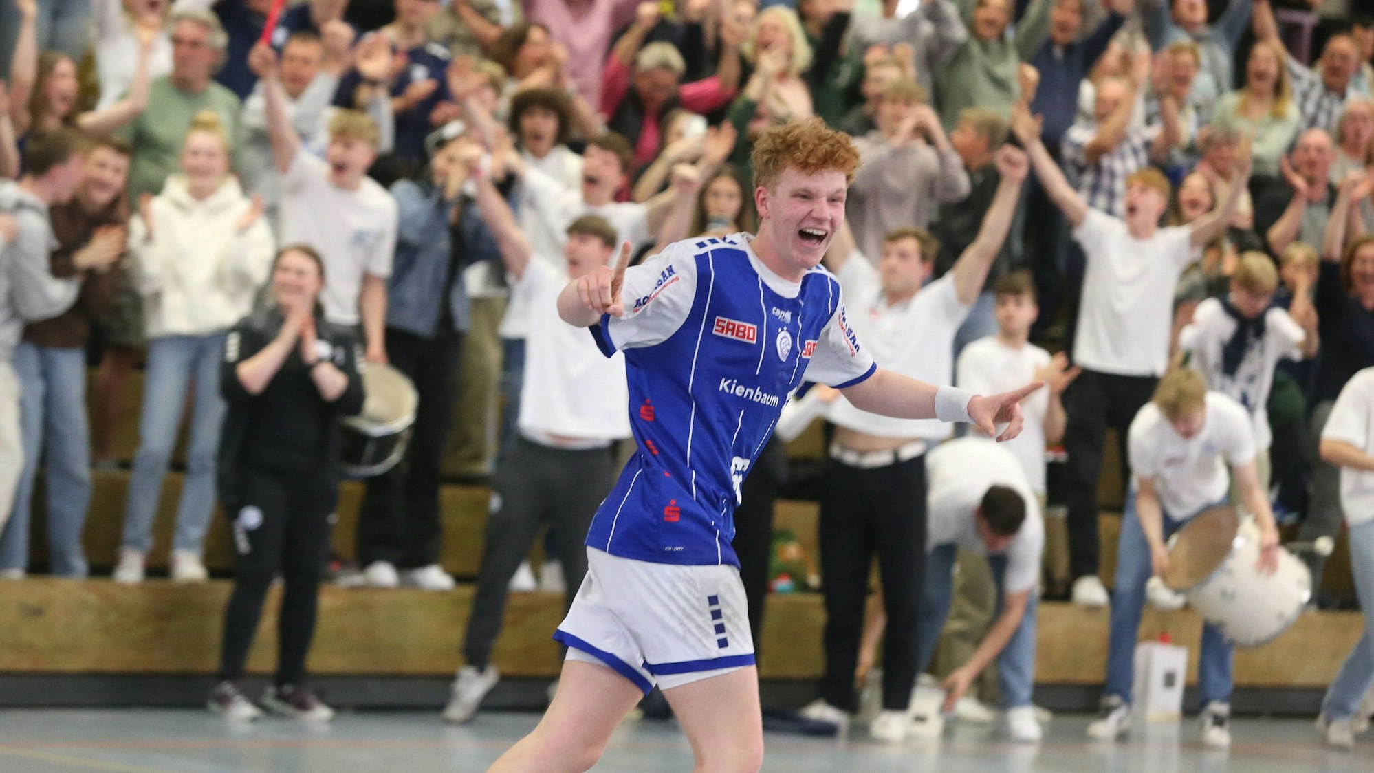 Jugendhandballer Julius Hein läuft jubelnd im Trikot des VfL Gummersbach die vollbesetzten Räng der Schwalbe-Arena entlang.