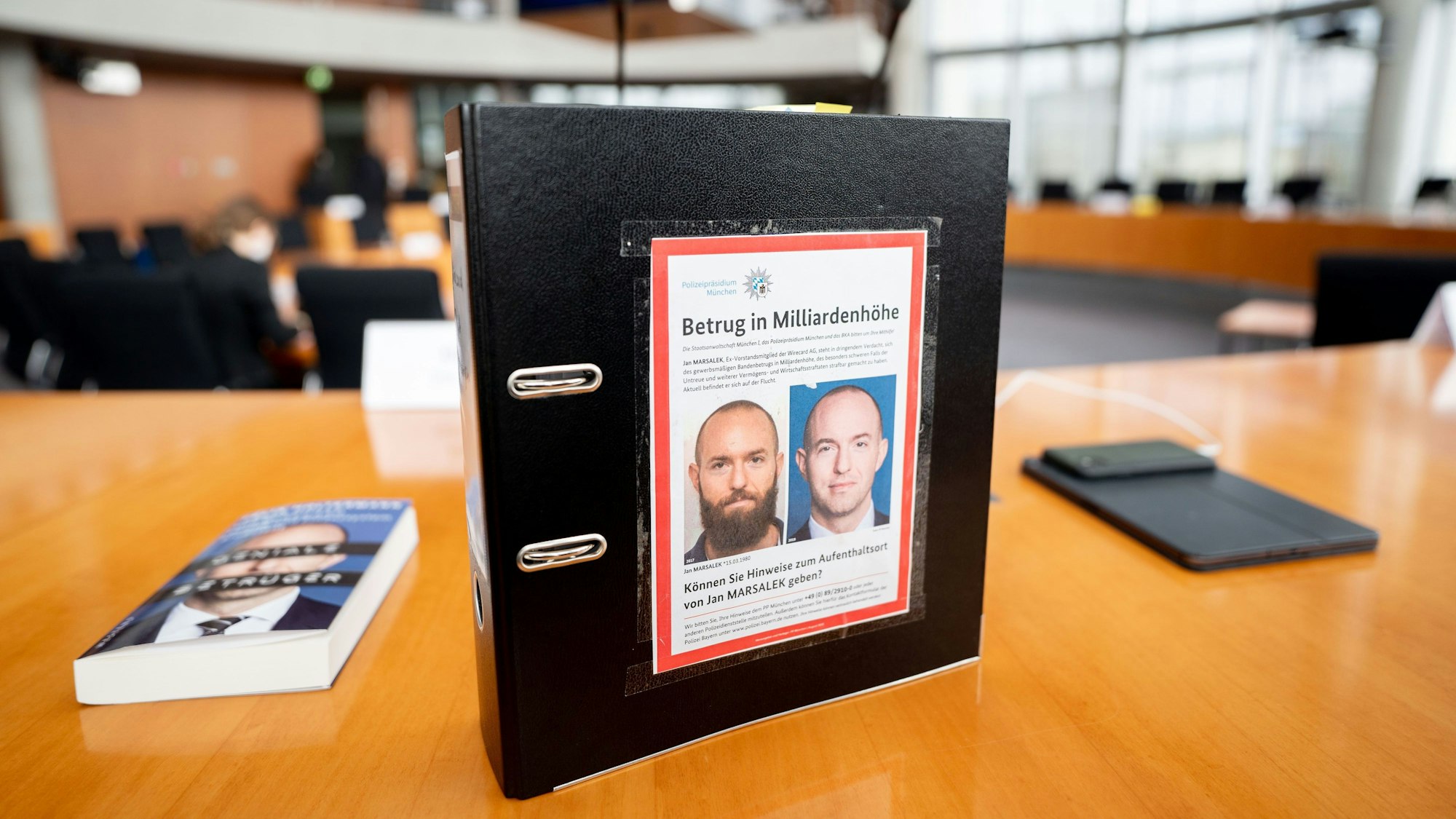 Ein Aktenordner mit Fahndungsfotos von Ex-Wirecard-Manager Jan Marsalek