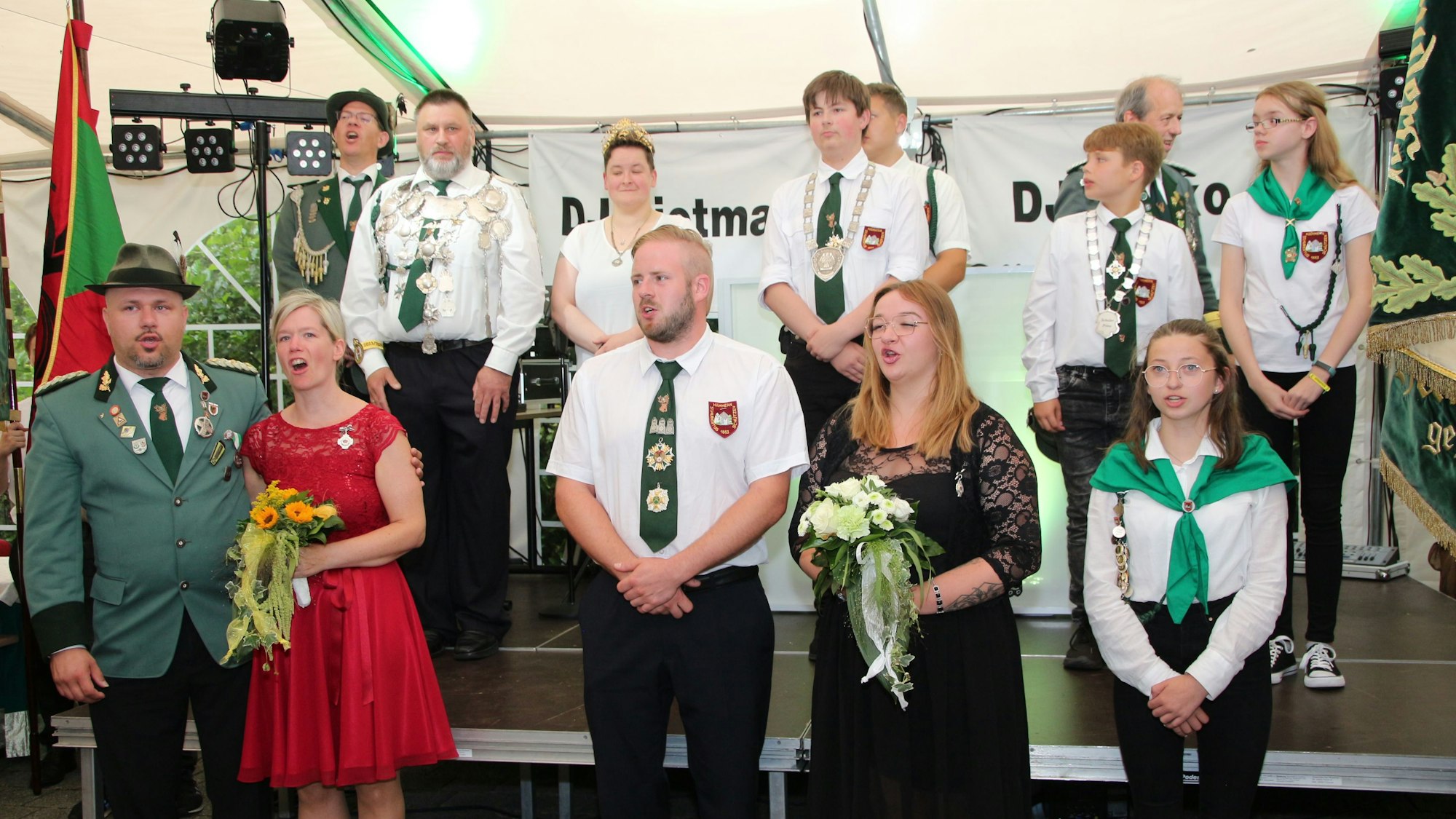 Schützen in Wipperfürth-Hämmern in Uniform stehen in einer Gruppe zusammen und singen.