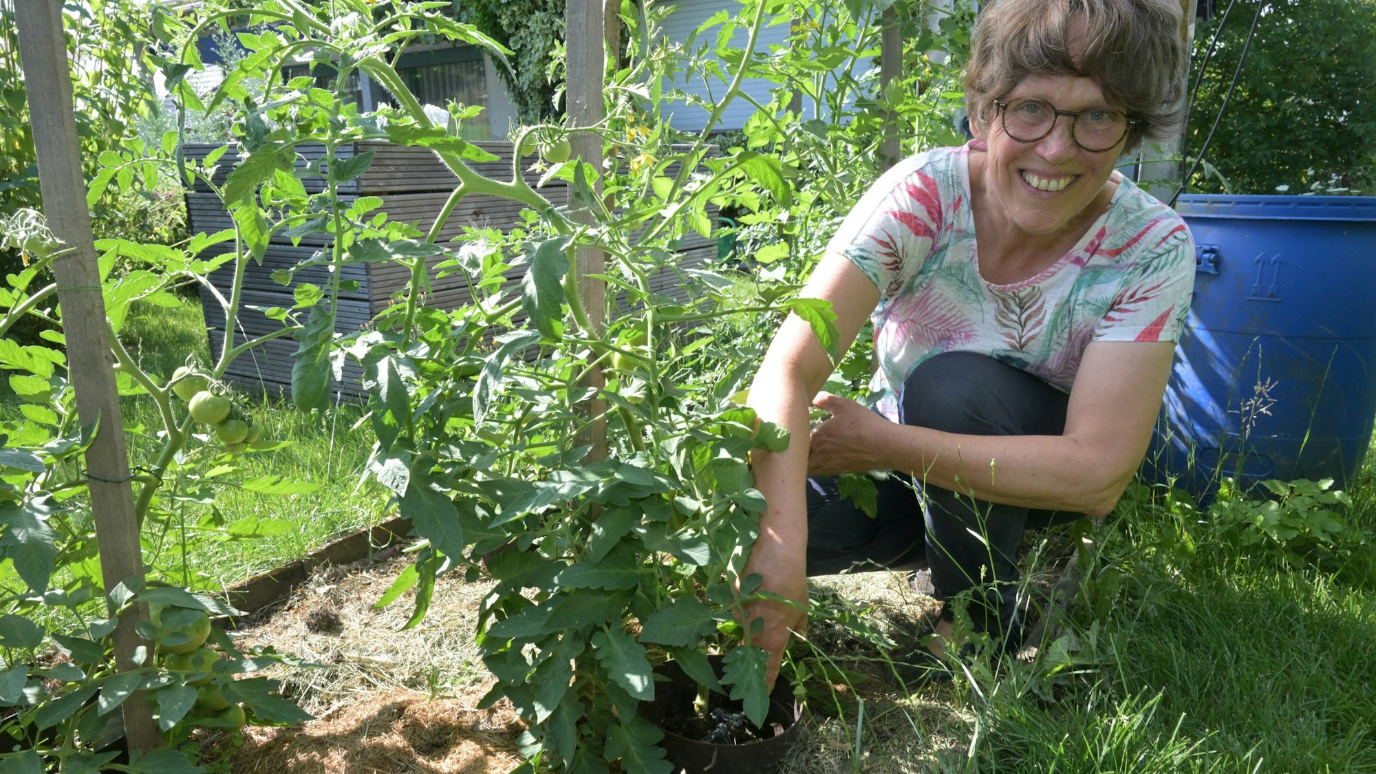 Heike Häusler hockt vor einer Pflanze.