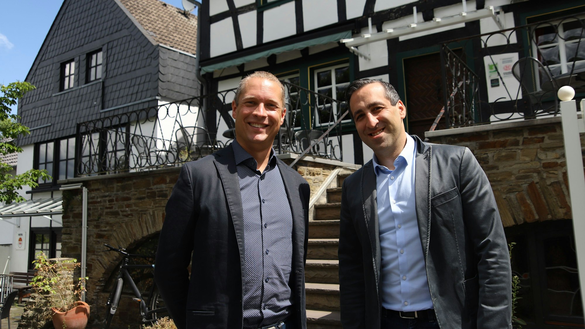 Zwei Männer stehen vor einem Fachwerkhaus.