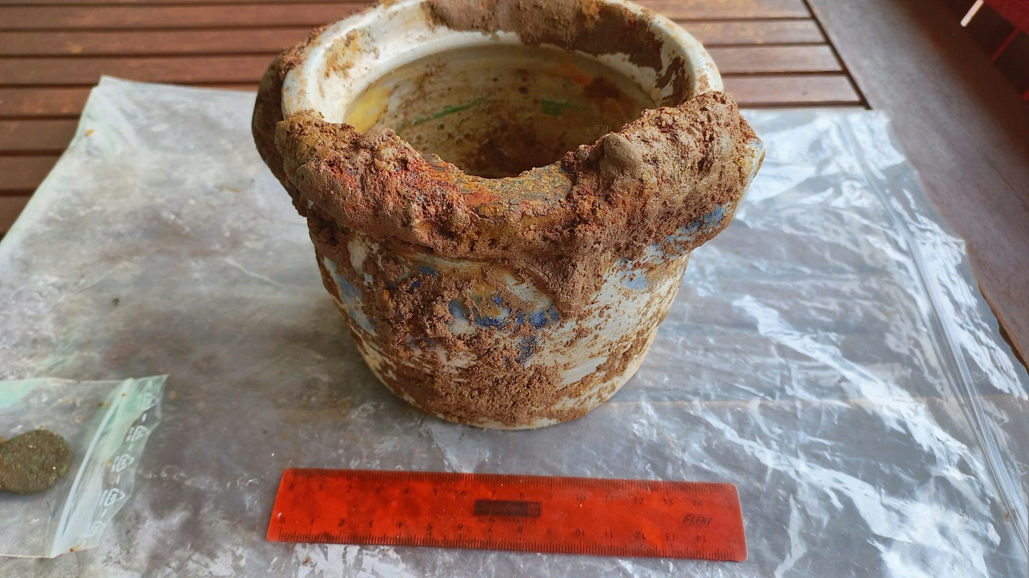 Die weiß-blaue Färbung des verkrusteten Gefäßes ist zu erkennen. Davor liegt ein Lineal zu Größenbestimmung.