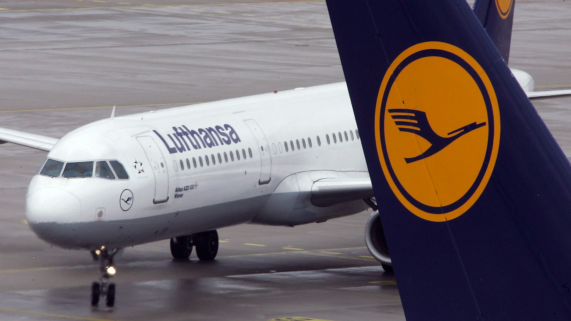 Ein Airbus A321 der deutschen Fluggesellschaft Lufthansa steht auf dem Rollfeld des Flughafens München. Im Vordergrund ist eine Heckflosse eines anderen Flugzeugs mit dem Lufthansa-Logo zu sehen. (Symbolbild)
