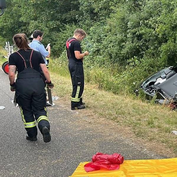 Das Bild zeigt Einsatzkräfte der Feuerwehr an einem Auto im Graben.