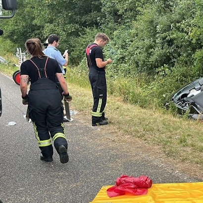Das Bild zeigt Einsatzkräfte der Feuerwehr an einem Auto im Graben.