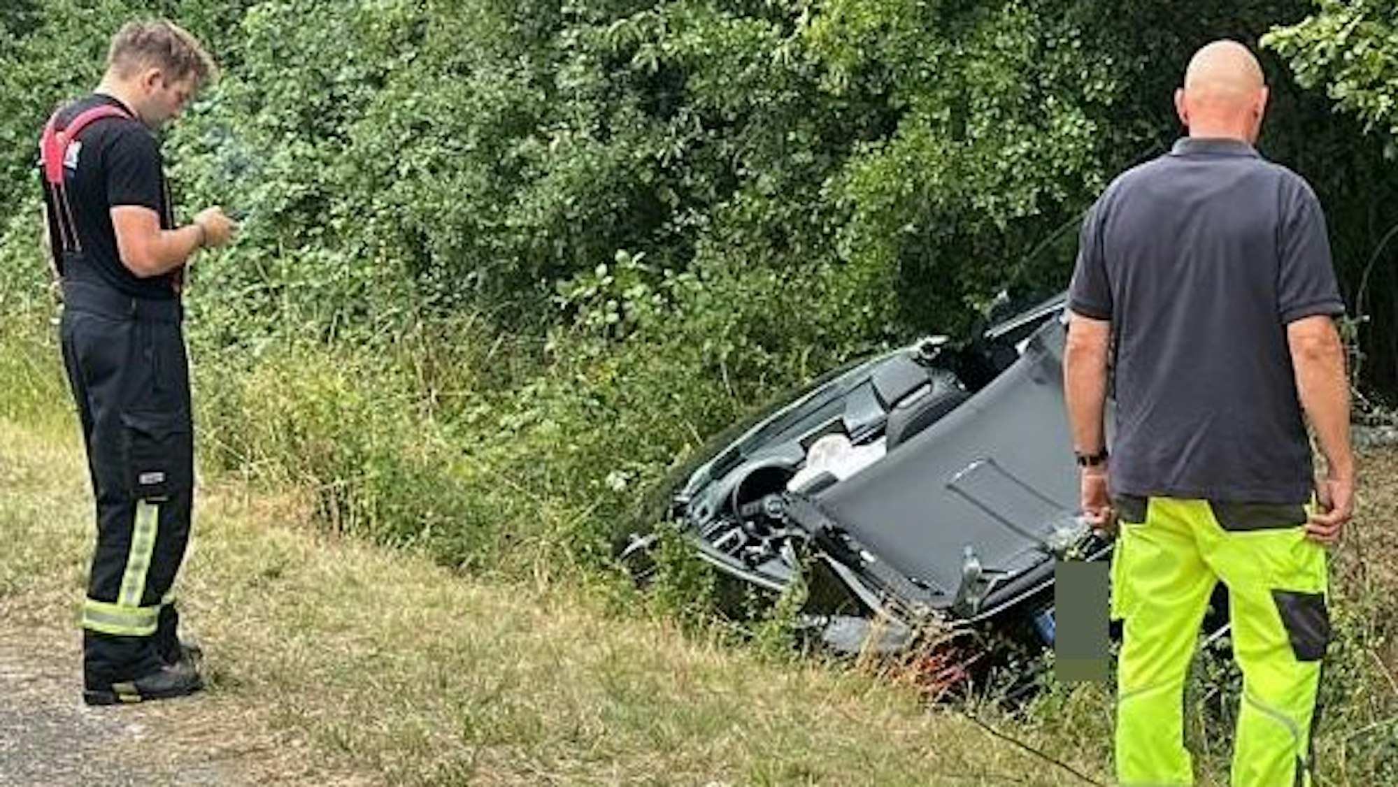 Das Bild zeigt Einsatzkräfte der Feuerwehr an einem Auto im Graben.