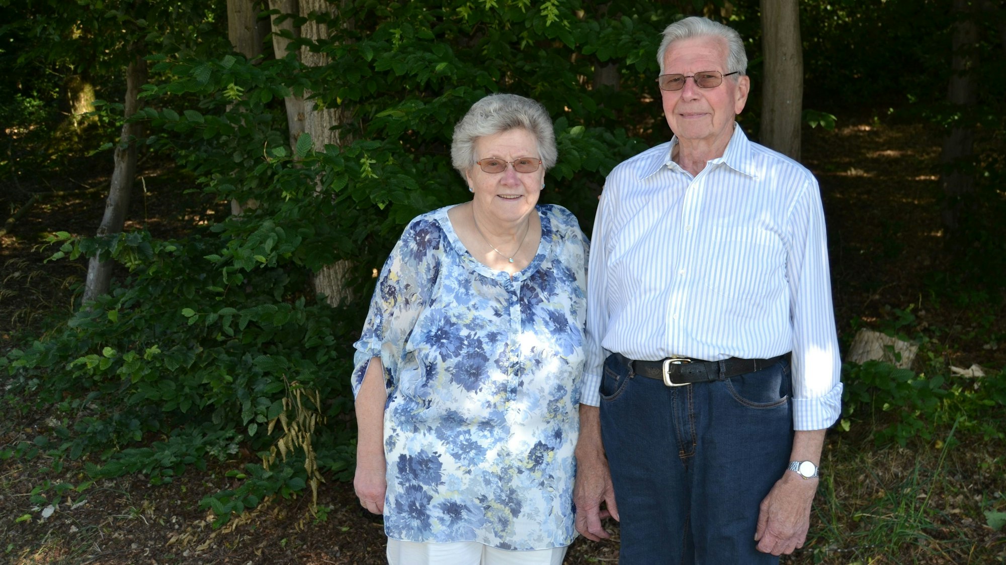 Ein älteres Ehepaar steht im Grünen nebeneinander.
