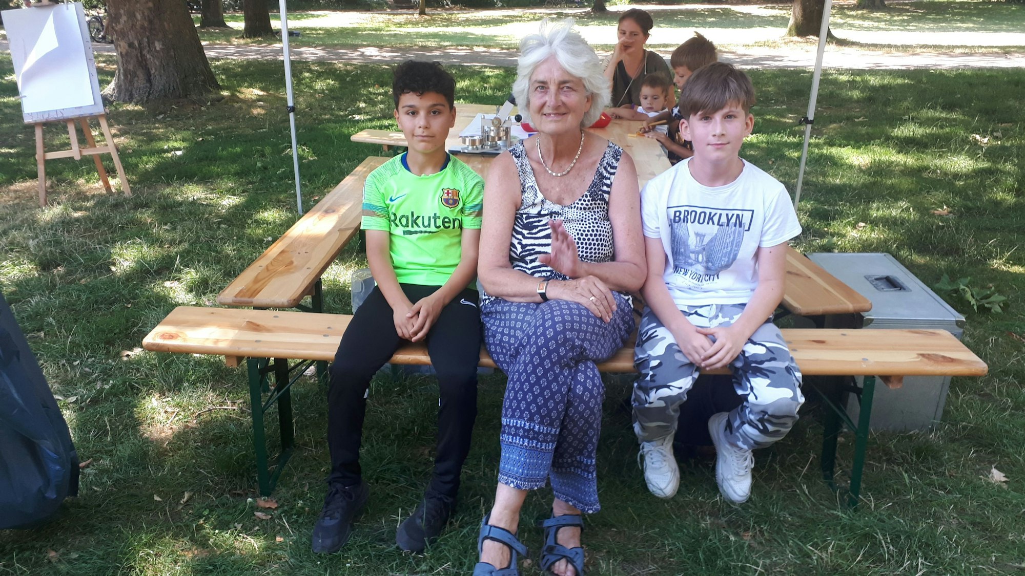 Inga Köstner sitzt mit Mariano und Rahman auf einer Bank.