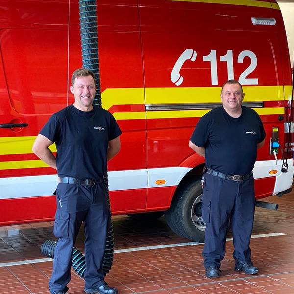 Zwei Männer stehen vor einem Einsatzwagen.