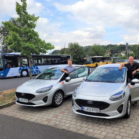 Auf dem Foto sind Laurenz Miehe (Cambio Rheinland) und Markus Auel (Gemeinde Kall) jeweils neben einem Ford Fiesta zu sehen.