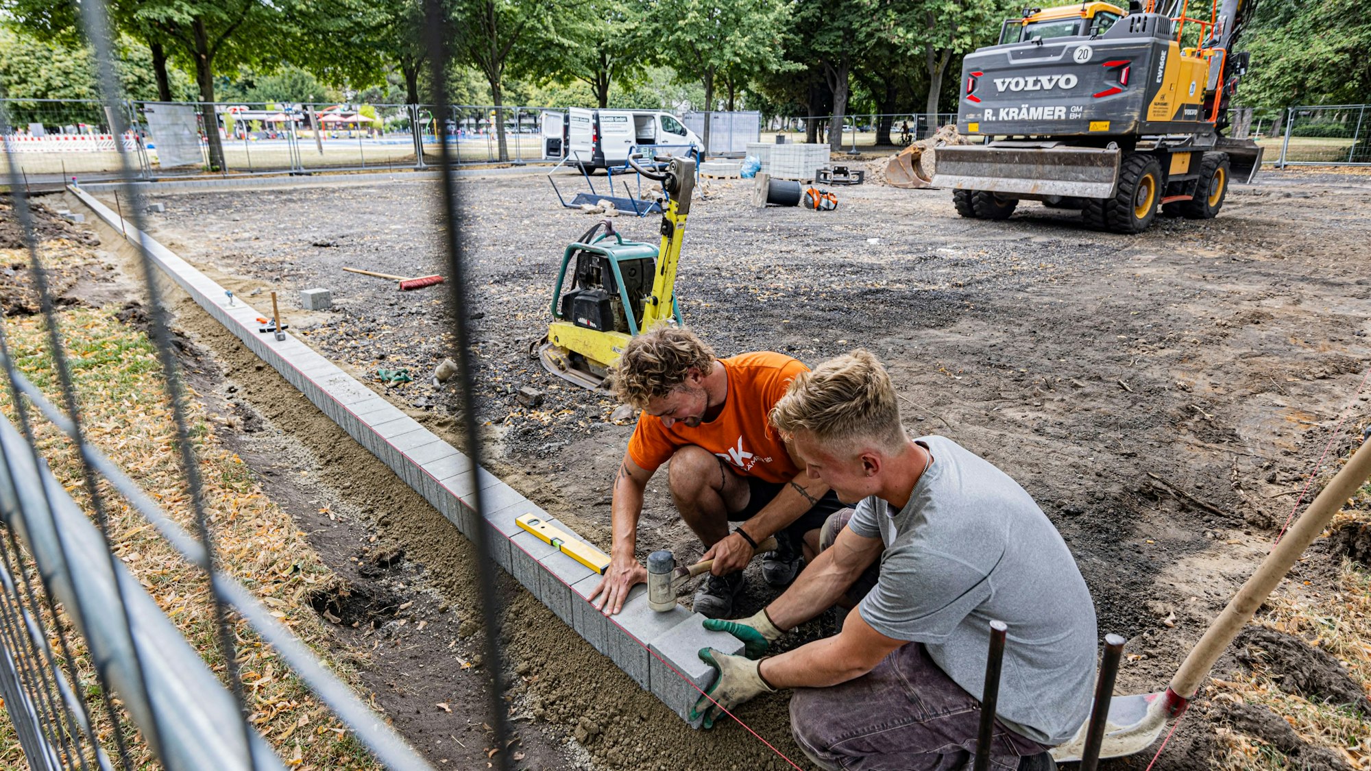Zwei Arbeiter bei den Sanierungsarbeiten des Tennisplatzes im Grüngürtel.