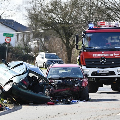 Zwei schwer beschädigte Kleinwagen stehen nach einem Unfall auf der Bundesstraße 506 bei Wipperfürth, im Hintergrund ein Feuerwehrfahrzeug und das Ortsschild von Lamsfuß.