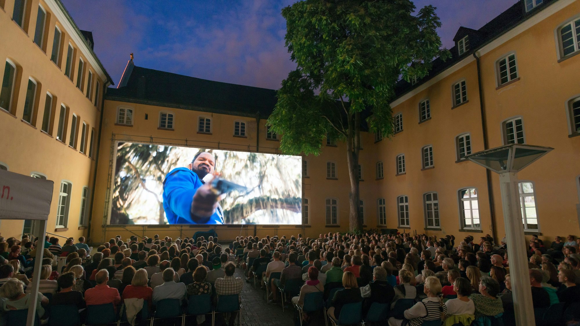 Zu sehen sind der vollbesetzte Innenhof und die große Kino-Leinwand.