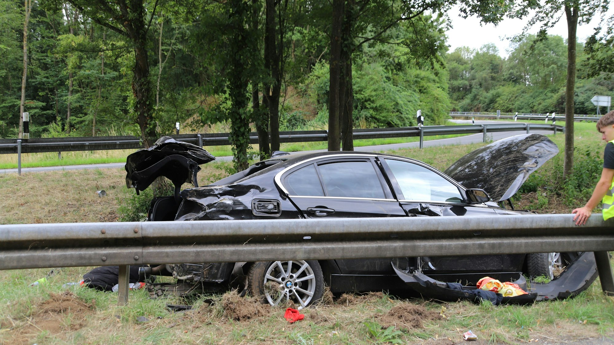 Ein schwer beschädigtes Auto steht neben einer Leitplanke.