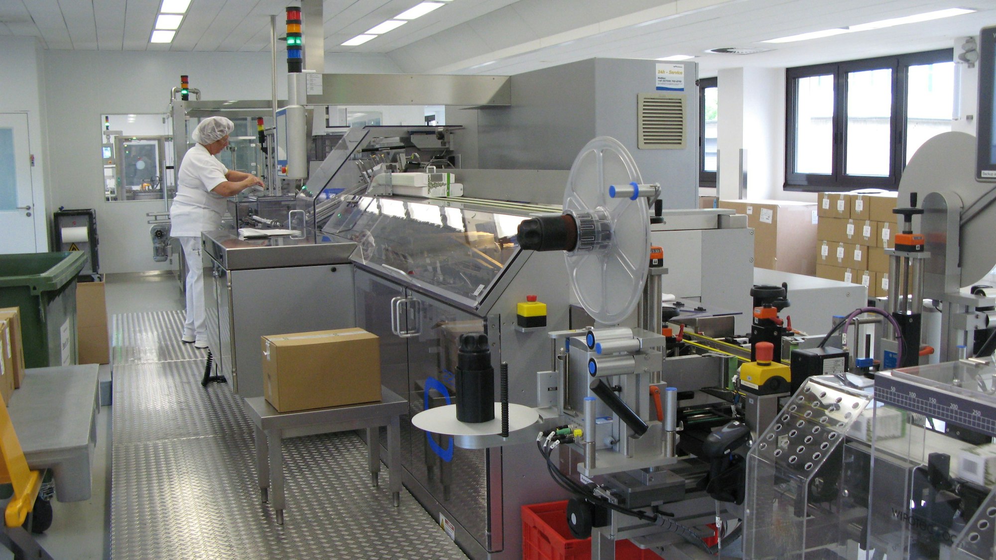 Eine Frau in weißer Schutzkleidung bedient eine Verpackungsanlage