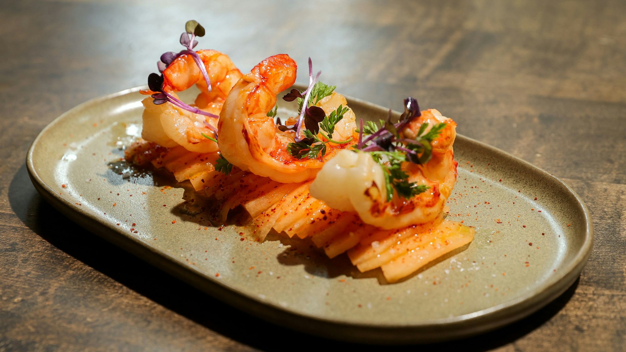 Auf einem Teller sind gebratene Wildfanggarnelen mit Melone angerichtet.
