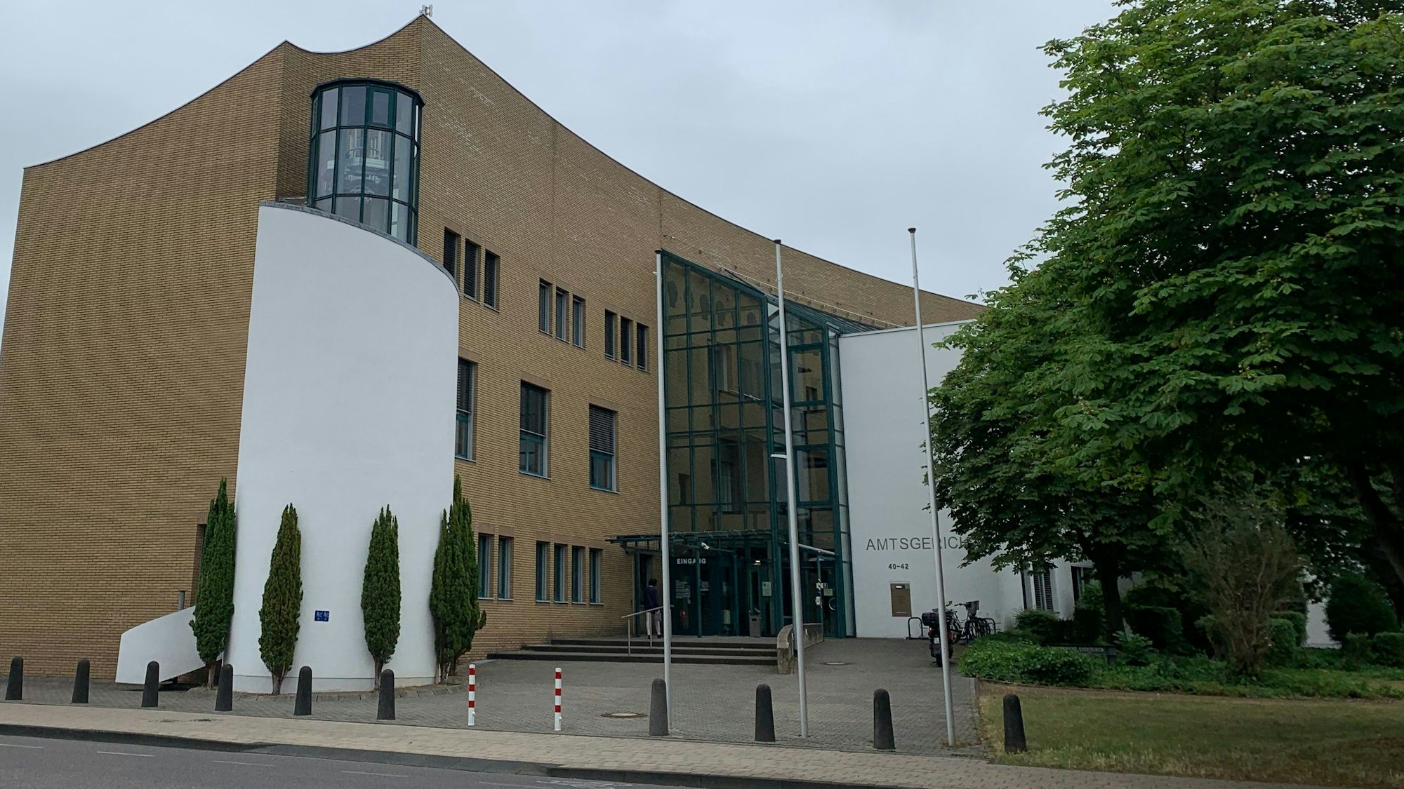 Das Amtsgerichtsgebäude an der Kölner Straße in Euskirchen. Es wird von Bäumen flankiert.