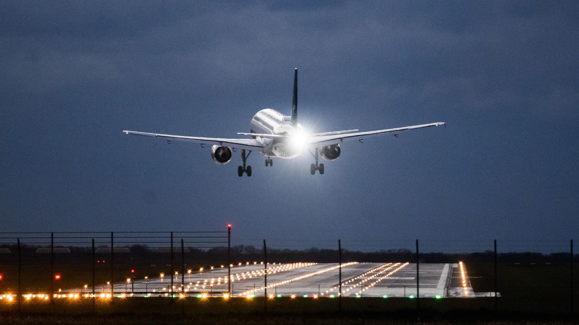 Ein Flugzeug steht kurz vor der Landung aufgrund von Windböen in deutlicher Schräglage in der Luft. (Symbolbild)
