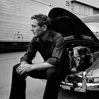 Das Foto aus dem Jahr 1967 zeigt den Schauspieler Paul Newman, der auf der Stoßstange eines VW Käfer sitzt.