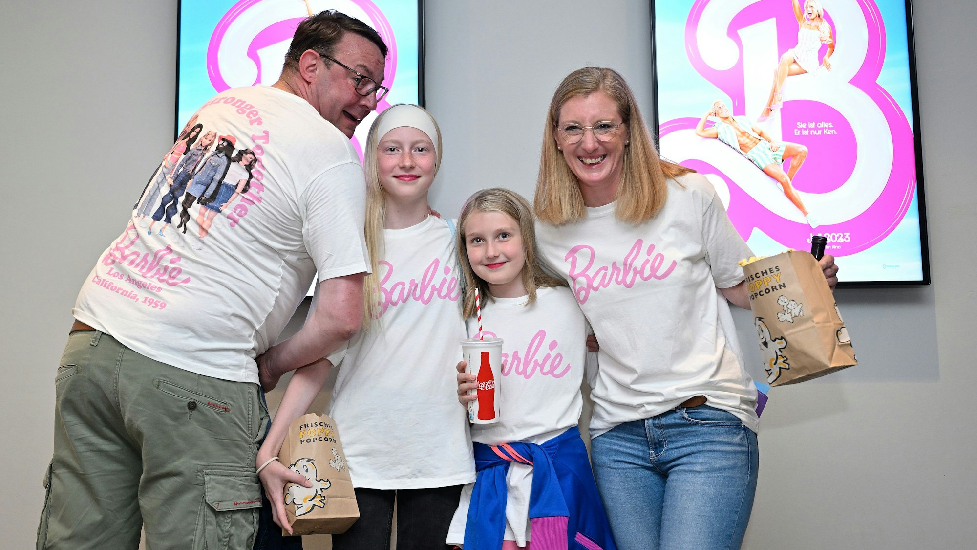 Familie Sauer steht vor Barbie-Plakaten.