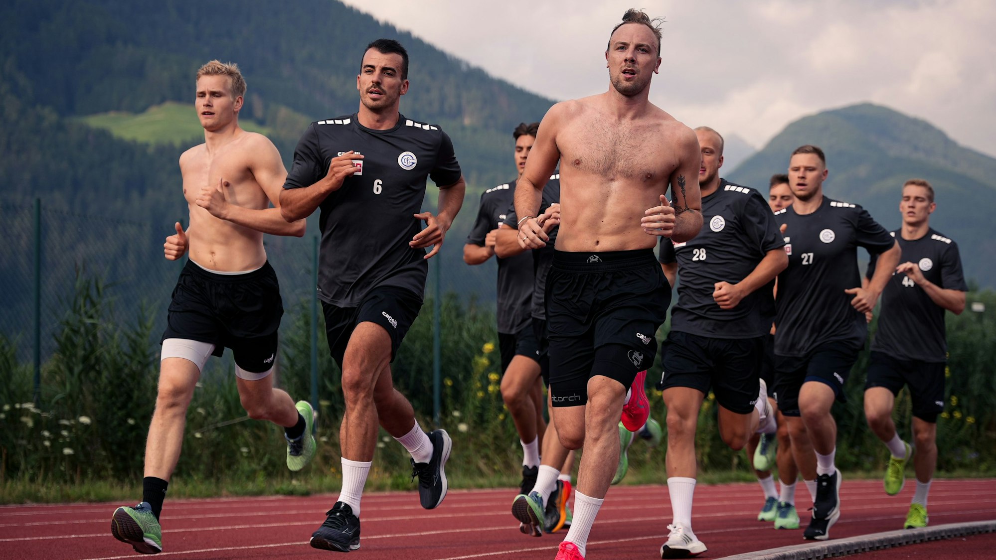 Eine Gruppe von Männern läuft, im Hintergrund die Alpen.