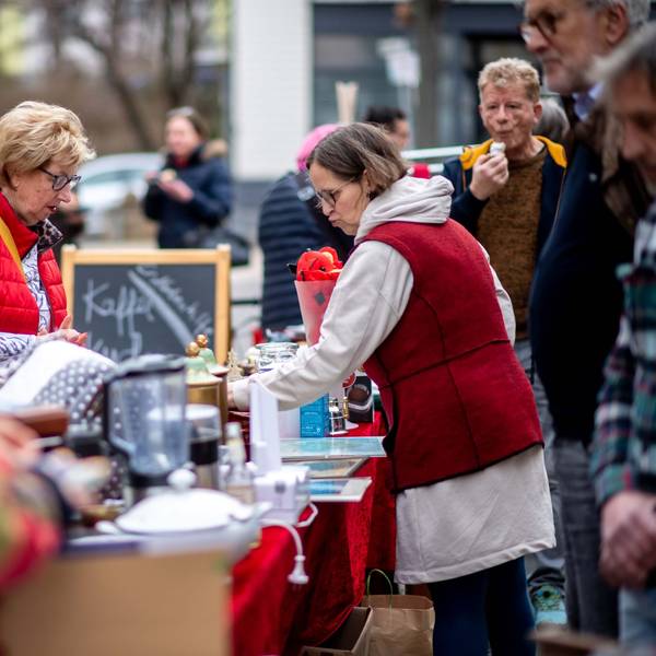 Das Bild zeigt einige Besucher des Trödelmarkts. Sie stöbern durch die angebotenen Artikel.